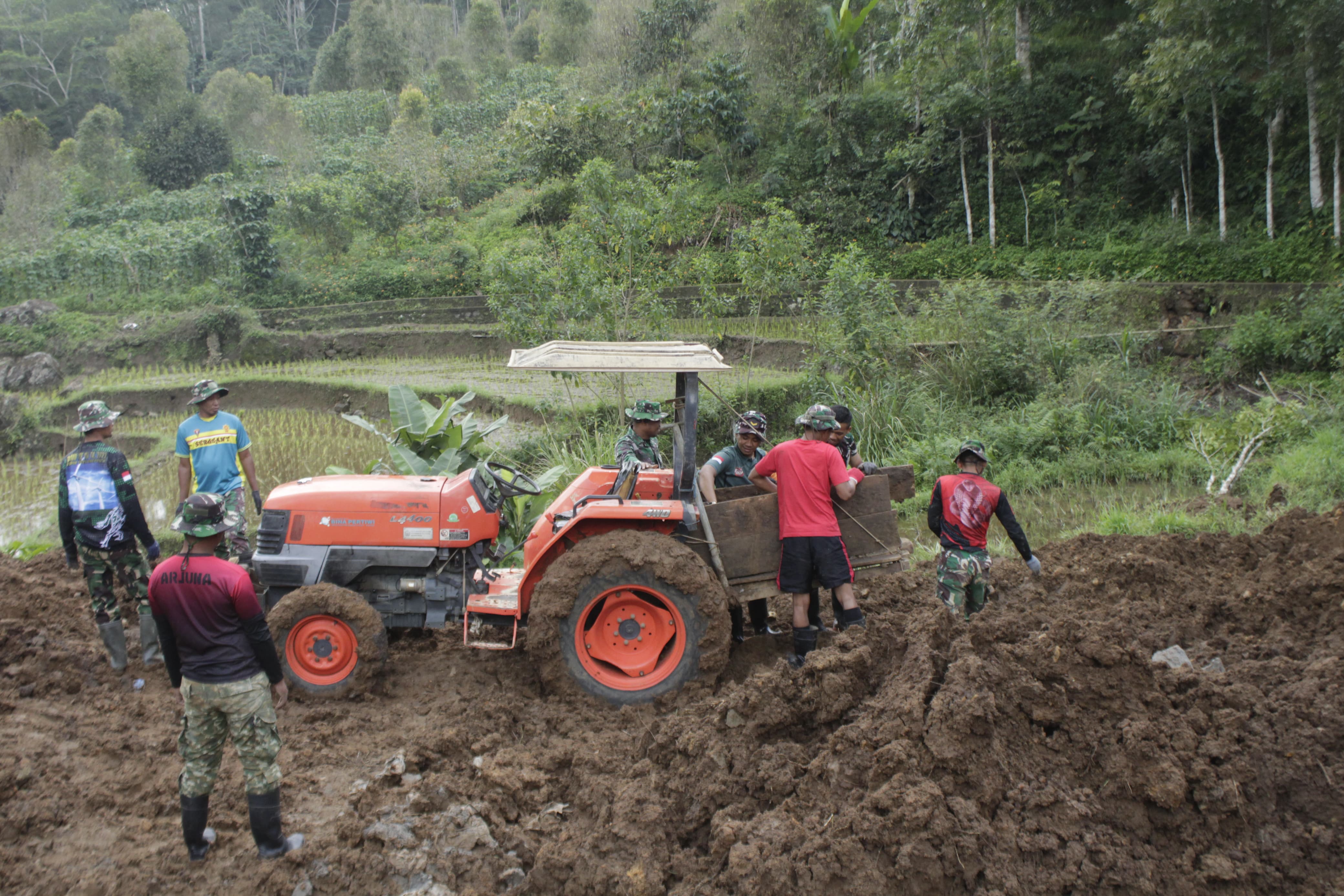 Feature Oleh : Letkol Arm Dian Akhmad Arifandi, S.E., M.Han. (Dansatgas TMMD Reh Ke 121 Kodim 1424/Sinjai) Kabut putih tebal menyelimuti setiap pagi Desa Arabika, sebuah desa kecil yang terletak di lereng Gunung Bawakaraeng, Kecamatan Sinjai Barat, Kabupaten Sinjai. Desa ini berada di ketinggian 2.840 meter di atas permukaan laut, membuatnya seolah-olah berada di atas awan. Suasana pagi di desa ini selalu tenang, seolah waktu berjalan lebih lambat di sini. Namun, ketenangan itu terganggu oleh raungan keras dari sebuah dump truck yang berjuang untuk bergerak maju di tengah lumpur. Hujan deras yang turun semalam membuat jalan tanah di desa ini berubah menjadi jebakan lumpur yang lengket. Ban kendaraan besar itu hampir separuh tenggelam, terjebak dalam kubangan lumpur yang mengancam kelancaran misi. Dump truck tersebut membawa material batu untuk pembangunan di lokasi kegiatan TMMD (TNI Manunggal Membangun Desa), sebuah inisiatif besar dari Kodim 1424/Sinjai. Kegiatan ini bertujuan membangun jembatan, lapis tebing, dan saluran gandeng—sarana vital bagi warga desa yang akan mendukung kesejahteraan dan mobilitas mereka. Di lokasi, sejumlah anggota Satgas TMMD Kodim 1424/Sinjai segera bereaksi, mencoba mendorong dump truck tersebut dengan sekuat tenaga. Namun, semua upaya tampak sia-sia. Lumpur yang licin membuat roda hanya berputar tanpa pergerakan berarti. Keringat mulai bercucuran, tetapi semangat tak pernah surut. Tim tahu, setiap detik yang terbuang akan memperlambat jalannya pembangunan yang sangat dibutuhkan warga desa. Situasi ini membuat kami berpikir keras. Jika masalah ini tidak segera teratasi, suplai material akan terhambat, mengganggu kelancaran pembangunan jembatan, lapis tebing, dan saluran gandeng—sasaran utama TMMD Reguler ke-121 Tahun 2024 kali ini.